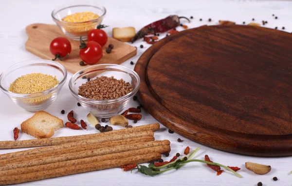 Alimentos orgânicos com placa de corte redonda marrom vazia na mesa de madeira branca — Fotografia de Stock