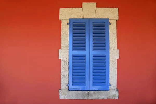 Vintage zamknięcie okna z okiennicami w kolorze niebieskim w stary stiuk czerwony dom — Zdjęcie stockowe