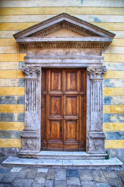 Μεσαιωνικά αρχαία ξύλινη πόρτα με περίτεχνες πέτρινες στήλες, Ιταλία. — Φωτογραφία Αρχείου