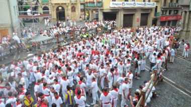 Crowds in traditional white shirts and red neck ties line the streets of Pamplona during the annual San Fermin festival. Basque country, Spain. - July 10, 2013 clipart
