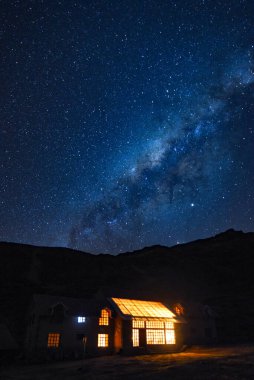 Milky Way and starry skies over a lodge in the Andes mountains.  clipart