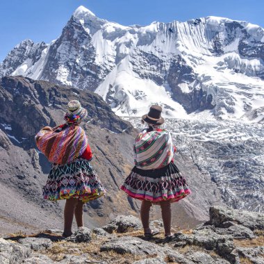 Quechua kızları Andean dağ manzarasına hayrandır. Cusco, Peru