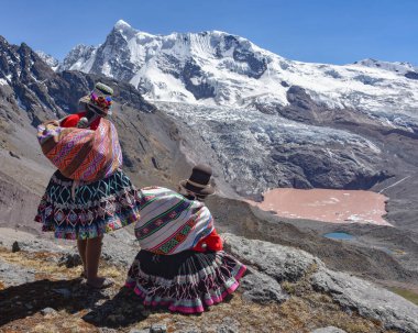 Quechua kızları Andean dağ manzarasına hayrandır. Cusco, Peru