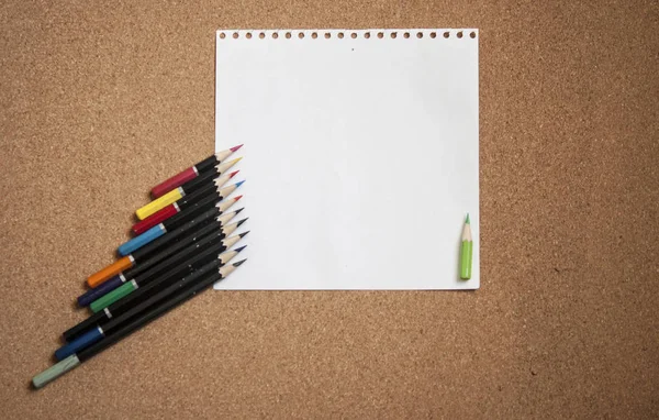 Διάφορα χρωματιστά μολύβια στο φόντο του πίνακα φελλού με λευκό shee — Φωτογραφία Αρχείου