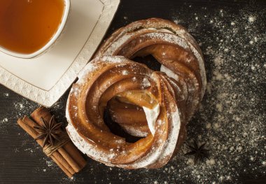 Yeni pişirilmiş geleneksel tarçın halkası, siyah tahta üzerinde girdap