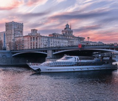 Moskova, Rusya - 15 Nisan 2017: Filo Radisson 'un gemisi gün batımında Moskova Nehri üzerinde yüzer. Gemi Borodino köprüsünün altından geçiyor..
