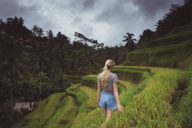 Sarışın kadın teraslı yamaçta bulutlu günde yürüyüş