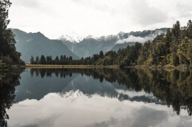 Mountain and trees reflection in lake Matheson, New Zealand. clipart