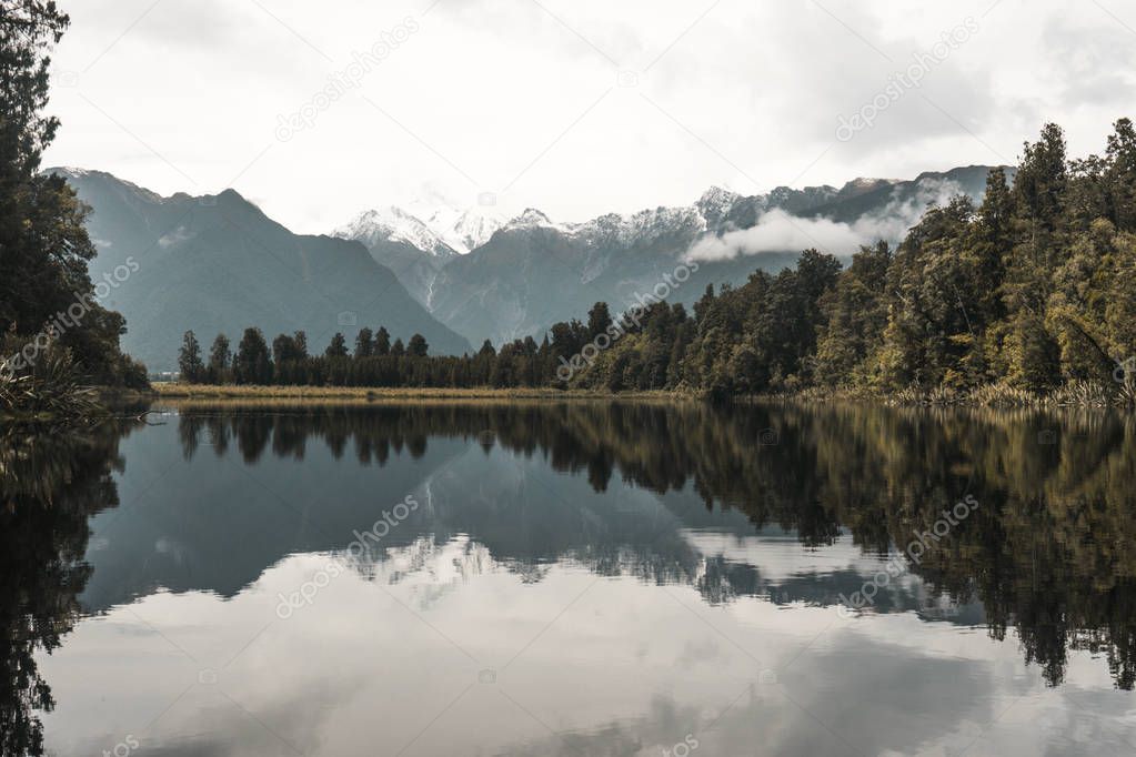 Mountain and trees reflection in lake Matheson, New Zealand.