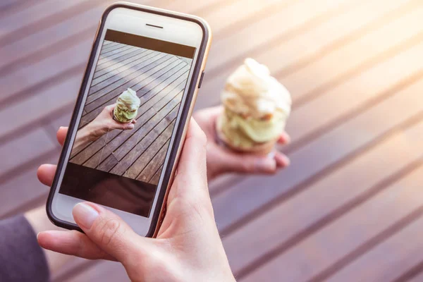 Young women with nice hands is taking a picture of italian artisanal ice cream with her smartphone