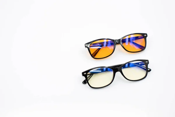 Beyaz zemin üzerinde izole edilmiş iki mavi ışık engelleyici gözlük (sarı ve turuncu lensler)