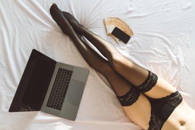 İnternet webcam modelinin (cam kız) çok para ile bilgisayar kamerasının önünde yatarken üst görünümü - sanal seks sohbeti kavramı