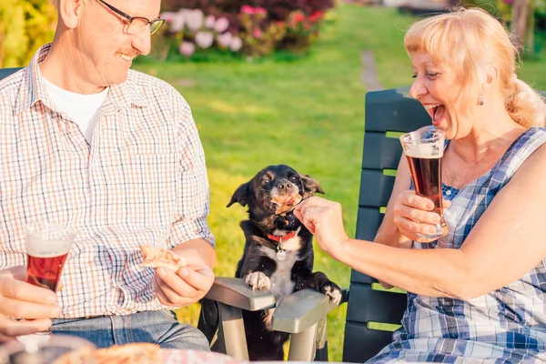 Glückliches Seniorenpaar Füttert Hund Mit Pizza Beim Hinterhof Dinner — Stockfoto