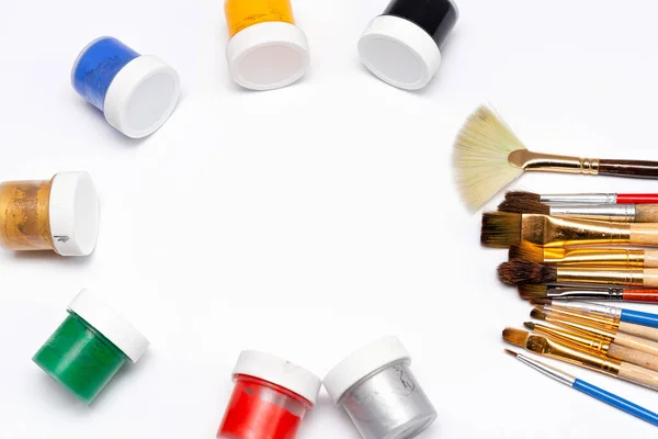 paint brushes and jars of paints on a white background