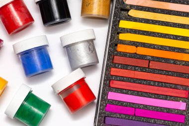 Kutudaki pastel boya kalemleri ve beyaz arka plandaki kavanozları boyamak için boya.