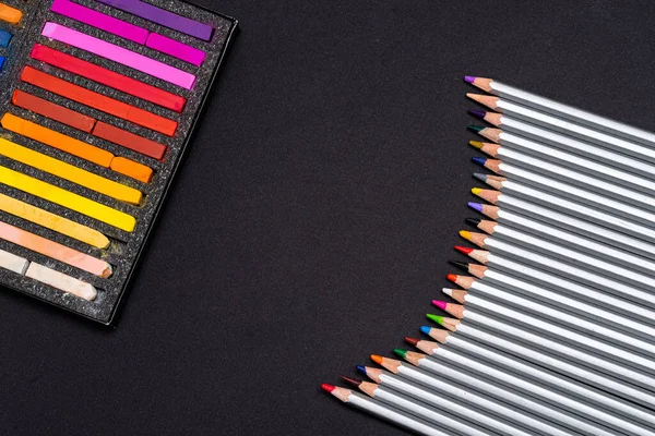 pastel crayons for drawing in a black box and color pencils for drawing on a black background