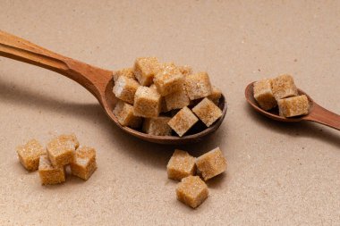 kahverengi rafine şeker iki tahta kaşıkta arka planda el işi kağıt üzerinde