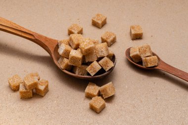 kahverengi rafine şeker iki tahta kaşıkta arka planda el işi kağıt üzerinde