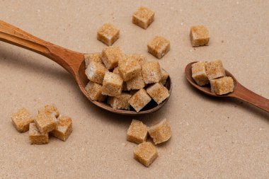 kahverengi rafine şeker iki tahta kaşıkta arka planda el işi kağıt üzerinde