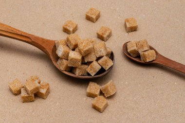 kahverengi rafine şeker iki tahta kaşıkta arka planda el işi kağıt üzerinde