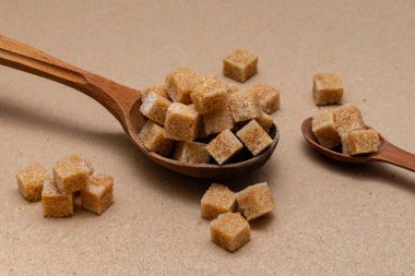 kahverengi rafine şeker iki tahta kaşıkta arka planda el işi kağıt üzerinde