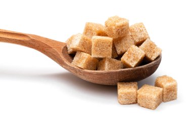 Tahta bir kaşıkta beyaz bir zeminde kahverengi rafine şeker.