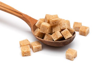 Tahta bir kaşıkta beyaz bir zeminde kahverengi rafine şeker.