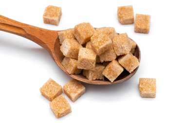Tahta bir kaşıkta beyaz bir zeminde kahverengi rafine şeker.