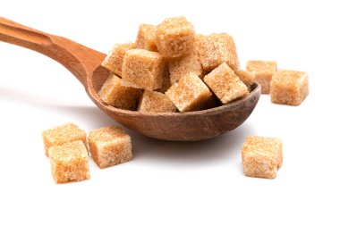 Tahta bir kaşıkta beyaz bir zeminde kahverengi rafine şeker.