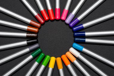 Siyah arka planda renkli çubukları olan gri tahta kalemler.