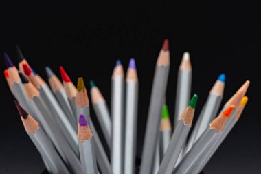 Siyah arka planda renkli çubukları olan gri tahta kalemler.