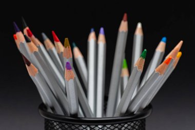 Siyah arka plan üzerinde renkli çubuklu gri tahta kalemler.