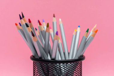 Gül arka planında renkli çubukları olan gri tahta kalemler.