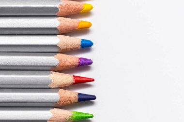 Beyaz arka planda renkli çubukları olan gri tahta kalemler.
