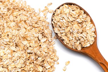 Beyaz arka planda yulaf ezmesi ve tahta kaşık.