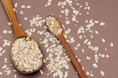 Kahverengi arka planda iki tahta kaşıkta yulaf ezmesi.