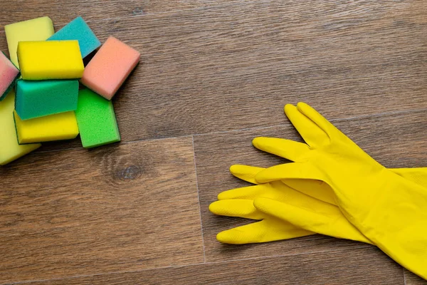 yellow rubber gloves and washcloths on wooden background