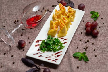 Havyar ve roka ile dilimlenmiş gözleme, bir bardak kırmızı şarap, kahve arka planında beyaz bir tabakta sos.