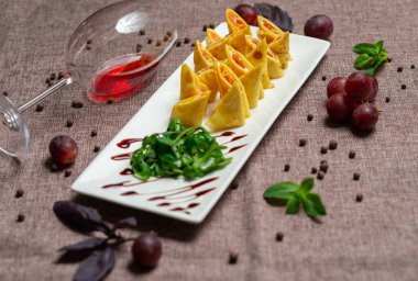 Havyar ve roka ile birlikte beyaz tabakta soslu dilimlenmiş gözleme, bir bardak kırmızı şarap, kahve arka planında beyaz bir tabakta sos.