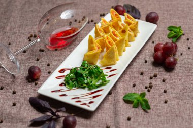 Havyar ve roka ile birlikte beyaz tabakta soslu dilimlenmiş gözleme, bir bardak kırmızı şarap, kahve arka planında beyaz bir tabakta sos.