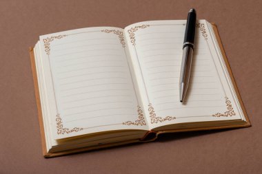 Kahverengi arkaplanda klasik defter ve kalem aç