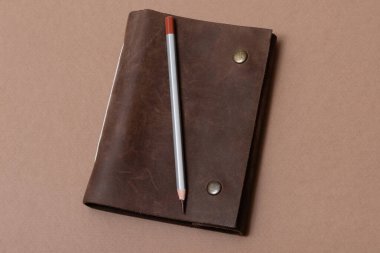 Kahverengi arka planda klasik deri defter ve kalem.