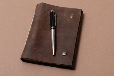 Kahverengi arka planda klasik deri defter ve kalem.