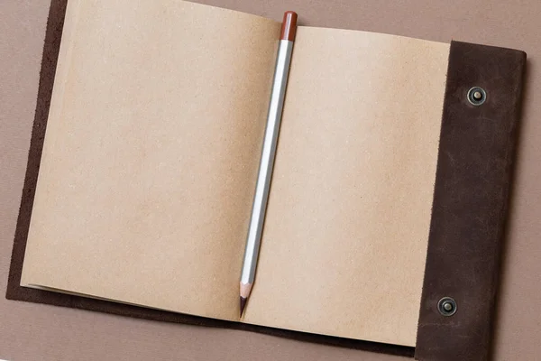 革カバーとグレーの鉛筆でコーヒーを背景にしたオープンクラフトノート — ストック写真