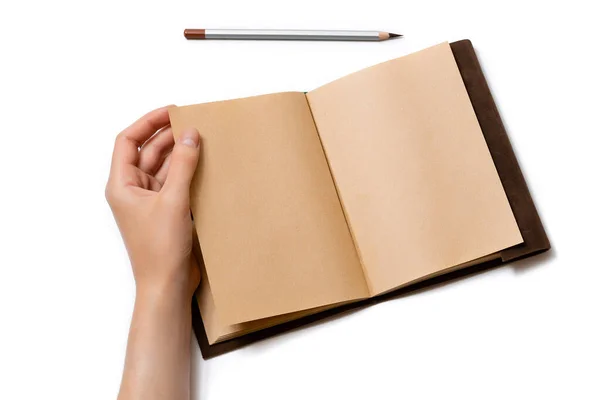 女性的手翻过一页打开的手工记事本 记事本上有一支白色背景的灰色铅笔 — 图库照片