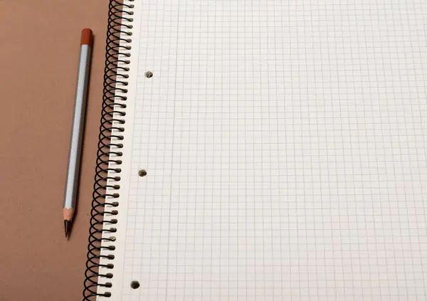 褐色背景的白色支票笔记本和灰色铅笔 — 图库照片