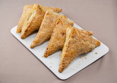 Dikdörtgen beyaz tabakta silan susam tohumlu Yahudi Boureka 'ları