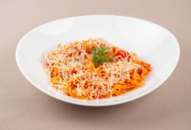 domates soslu makarna, peynir, mantar ve otlar bej kumaş arka planda beyaz bir tabakta.