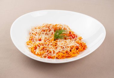 domates soslu makarna, peynir, mantar ve otlar bej kumaş arka planda beyaz bir tabakta.