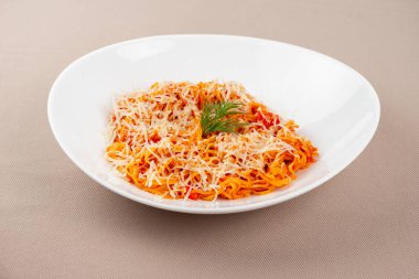 domates soslu makarna, peynir, mantar ve otlar bej kumaş arka planda beyaz bir tabakta.